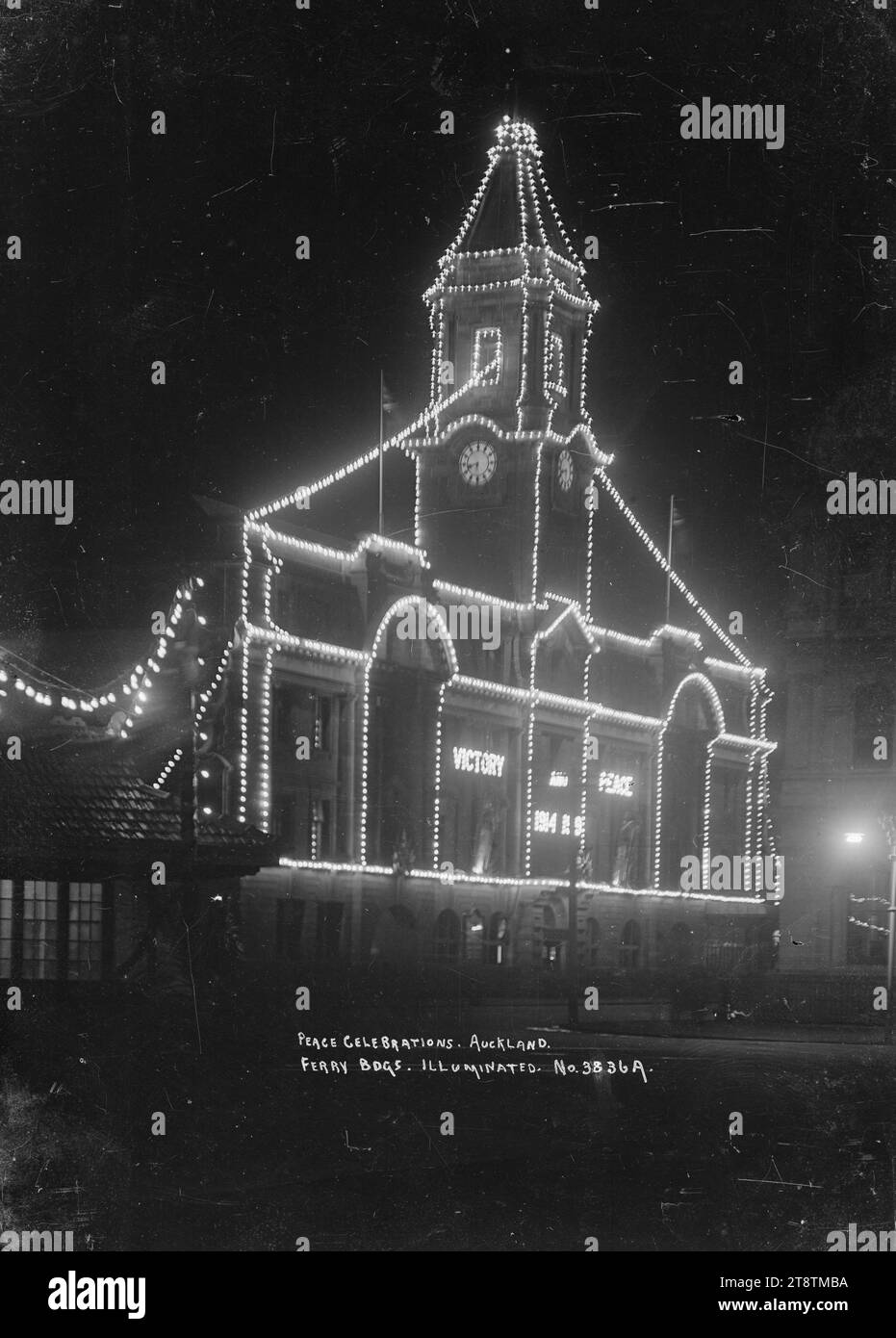 View of Auckland, New Zealand Ferry Building taken at night to show the Peace celebration illuminations, View of Auckland, New Zealand Ferry Building taken at night from the south side (front facade) showing the illuminations on the building. `Victory and Peace 1914 .. indecipherable' have been spelt out with lights on the front together with additional lights which outline the architectural features of the building. The illuminations were installed to celebrate the end of World War One Stock Photo
